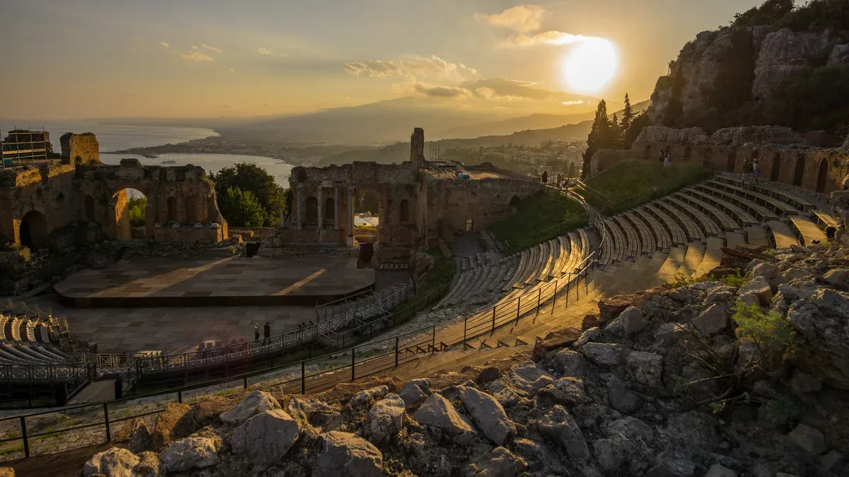 The Greek theatre of Taormina at sunset with Etna on the horizon, where Mount Etna tours from Taormina start, Sicily